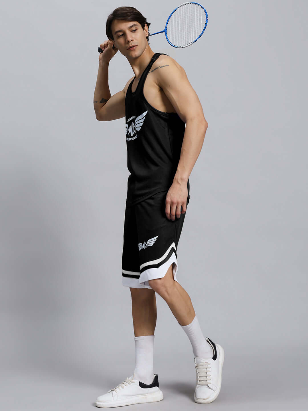 Man wearing WD WINGS GYM CO-ORD SET MEN BLACK playing badminton, showcasing comfortable and flexible athletic wear.