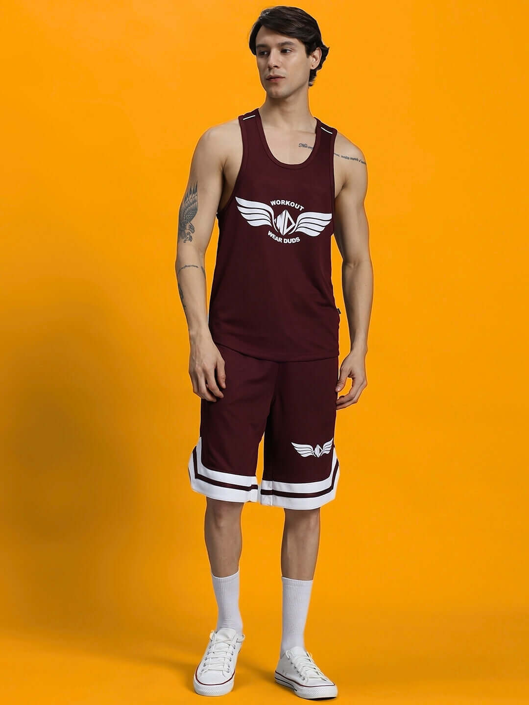 Man wearing a maroon WD Wings Gym Co-ord Set made of sports polyester, featuring a tank top and matching shorts against an orange background.