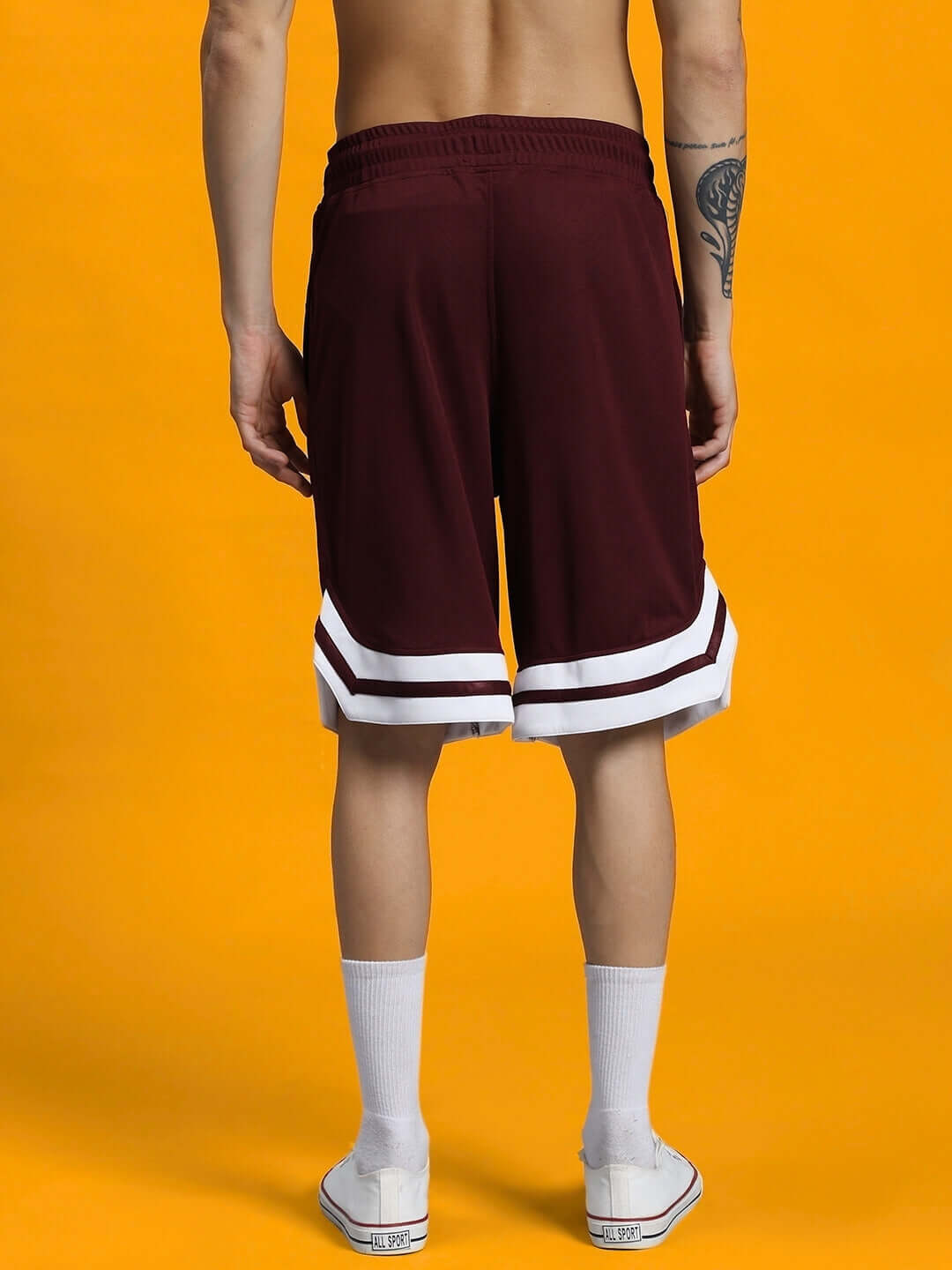 Back view of WD WINGS REGULAR FIT SHORTS MAROON showing design and length on a model against a yellow background.