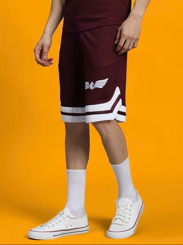 Person wearing WD WINGS REGULAR FIT SHORTS MAROON showcasing comfort and style against a vibrant background.
