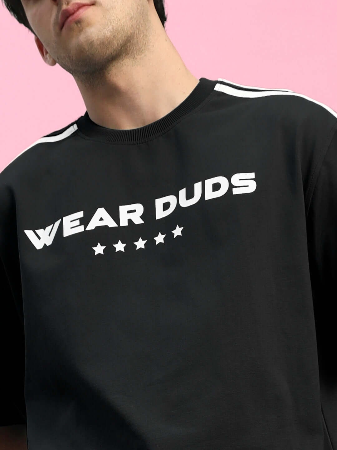 Man wearing black Wear Duds t-shirt with star design on pink background