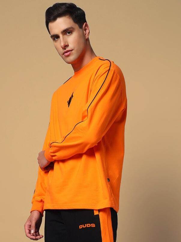 Model wearing WHOPPER Oversized Orange Sweatshirt made from premium cotton French terry, 240 GSM, with black piping detail.