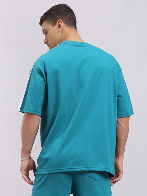 Back view of a teal Wideline oversized t-shirt made from premium cotton French terry, worn by a model, highlighting comfort and style.