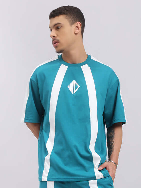 Model wearing a teal oversized T-shirt with white stripes, made from premium cotton French terry and elastane, by Color By Colours.
