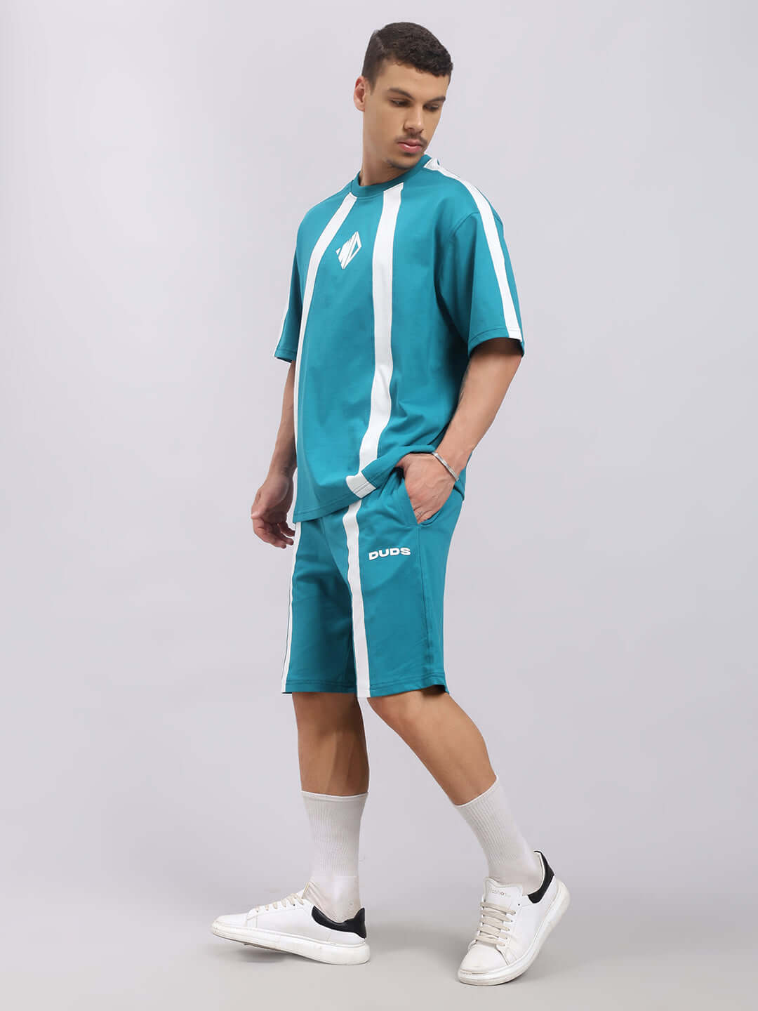 Model wearing teal WIDELINE oversized t-shirt, made from premium cotton French terry, styled with white sneakers.