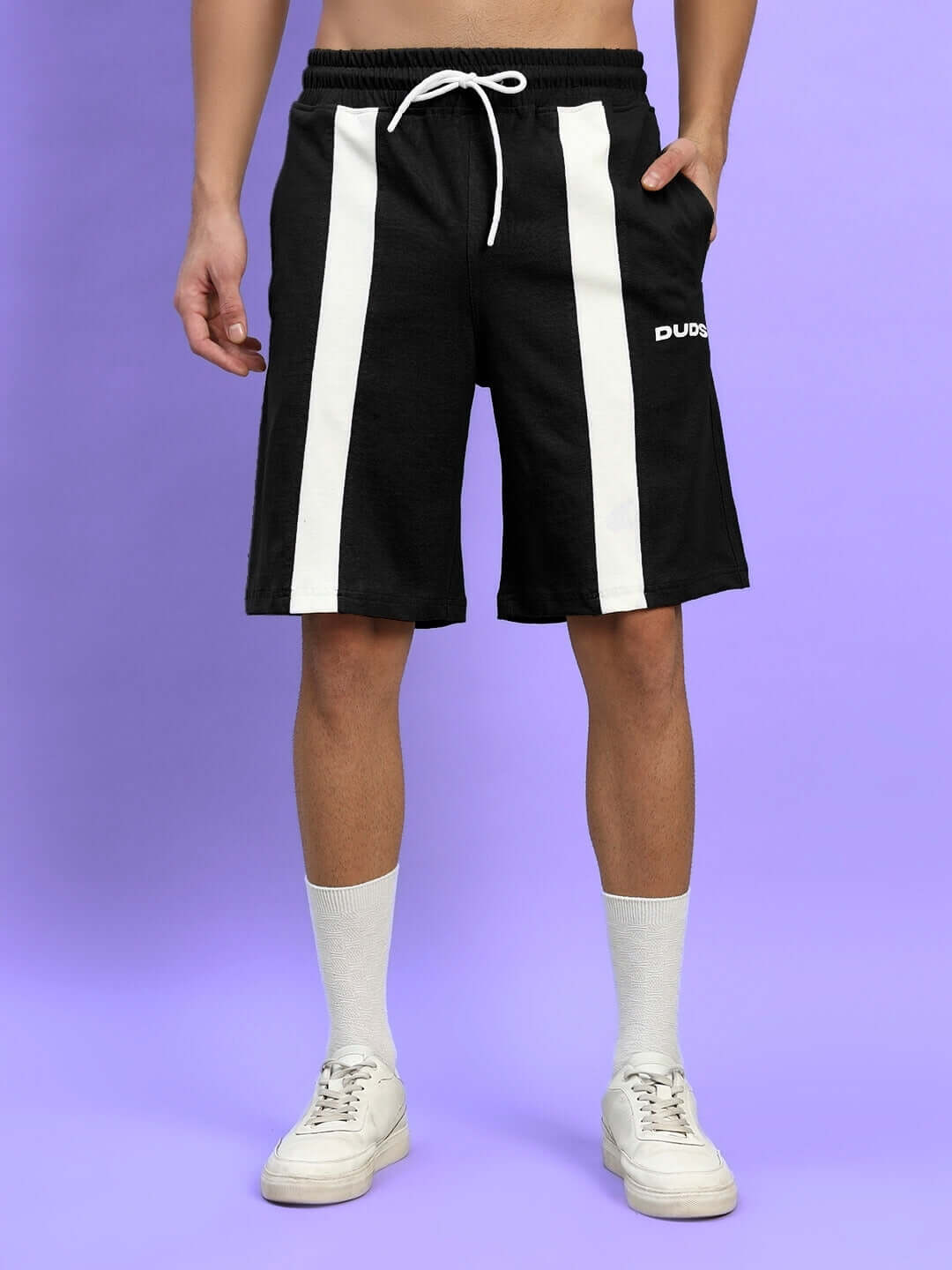 Black WIDELINE regular fit shorts with white stripes, available for custom size, shown worn by model against a purple background.