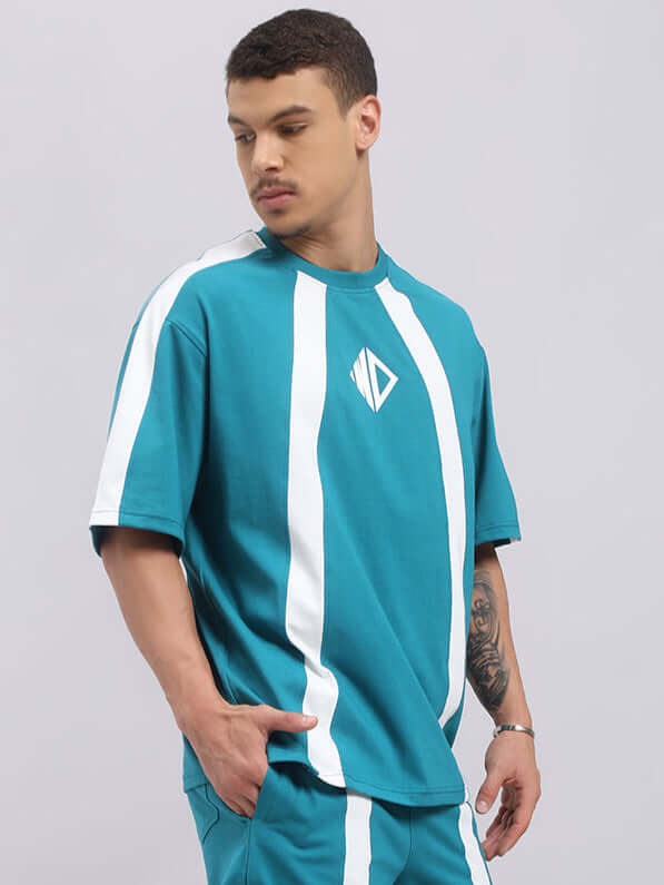 Model wearing a teal Wideline oversized T-shirt, featuring white stripes and a unique logo. Made from premium cotton French terry.