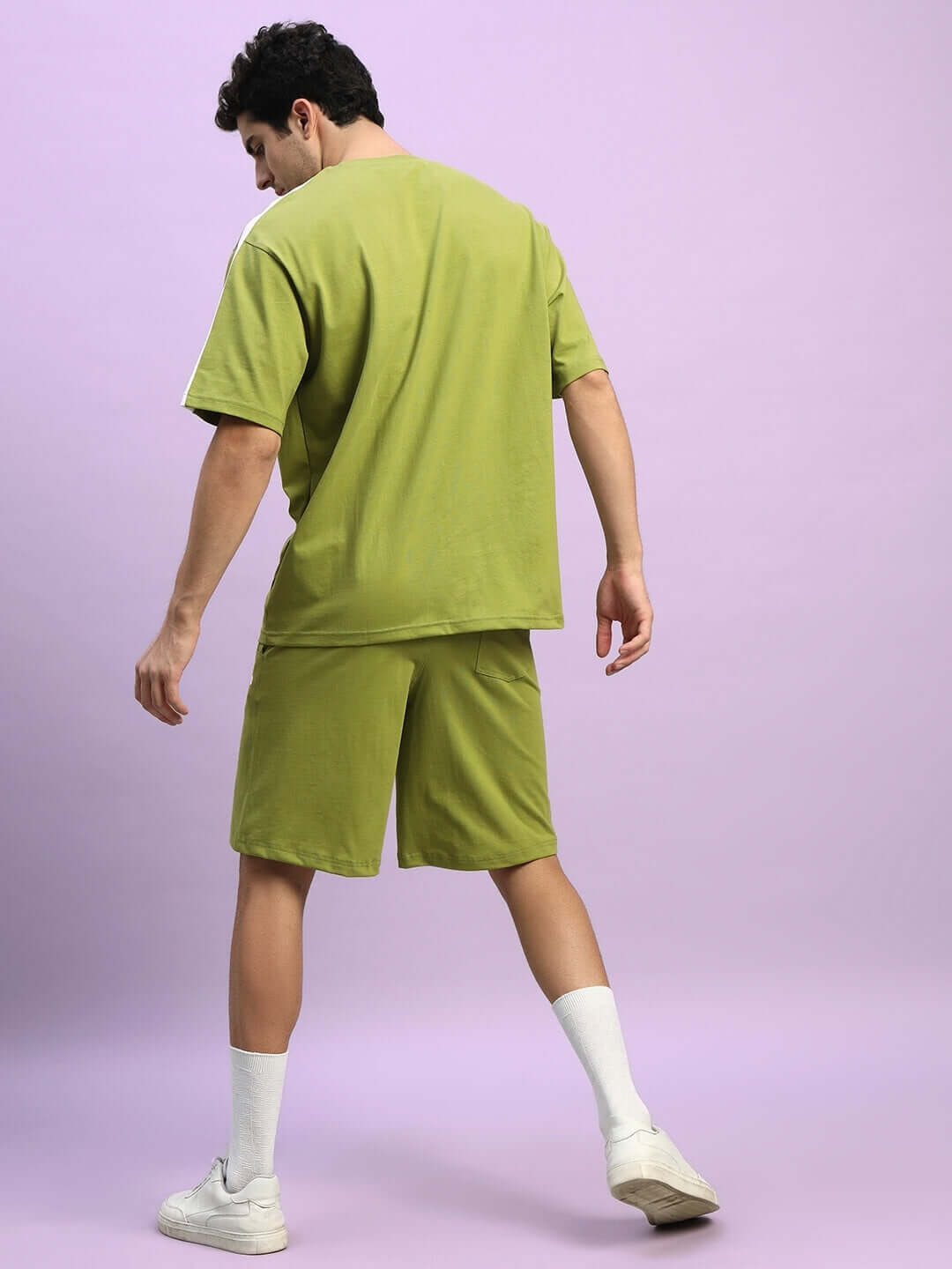 Man wearing WIDELINE SUMMER CO-ORD SET OLIVE GREEN showing back view on purple background.