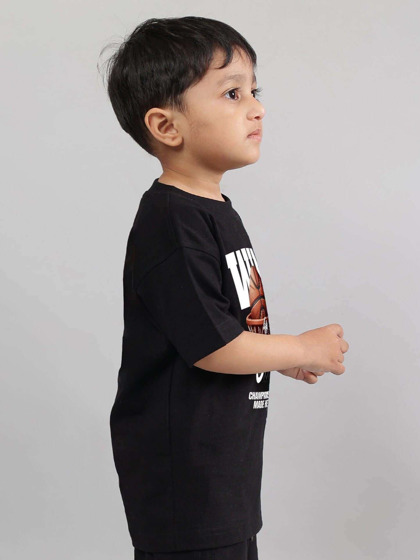 Child wearing black WIN DAY T-shirt for boys and girls, made by DUDS, showcasing custom fit and design options by experienced tailors.