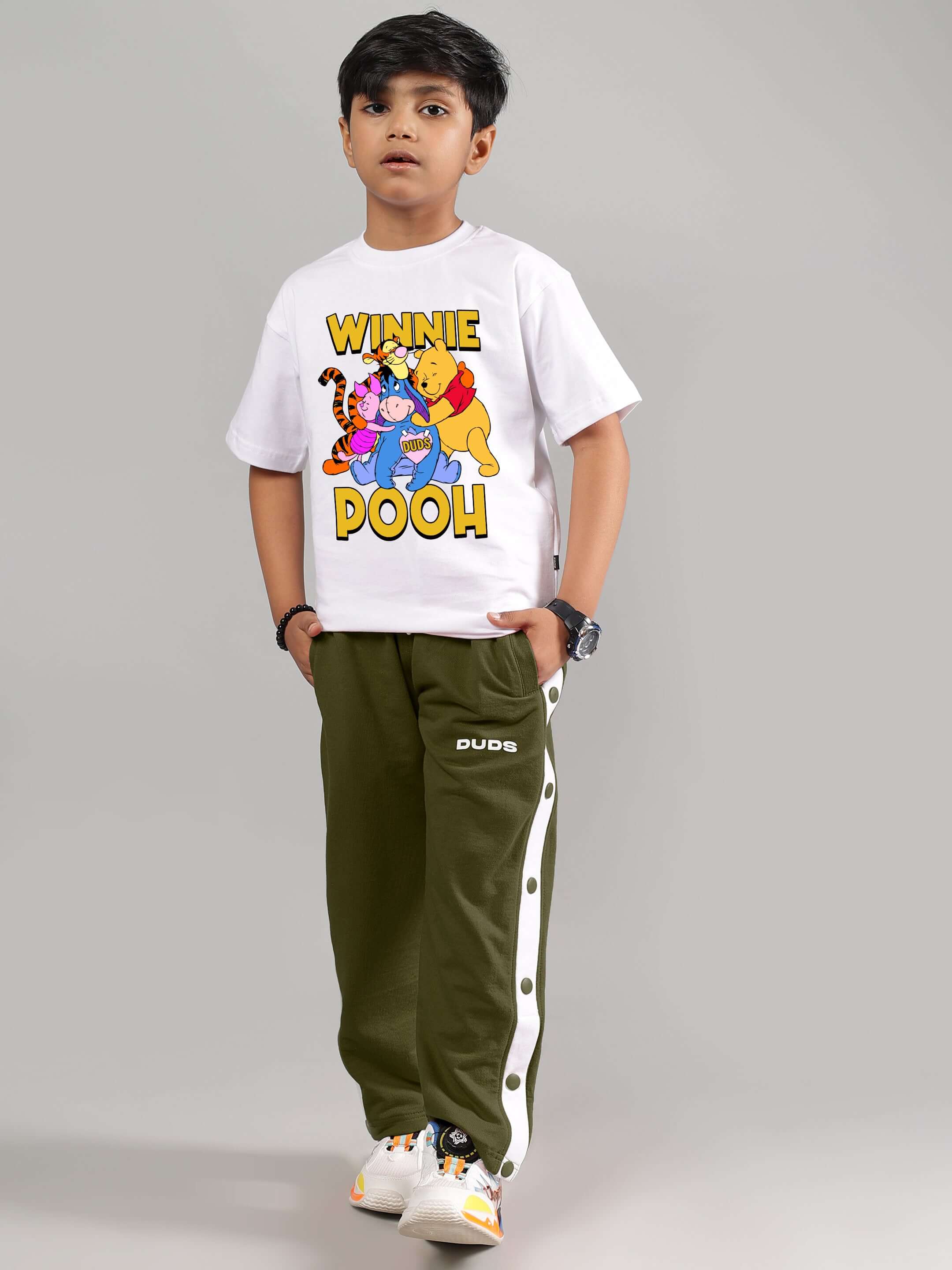 Boy wearing white Winnie the Pooh shirt and olive green trousers from DUDS, customizable fit available for boys and girls.