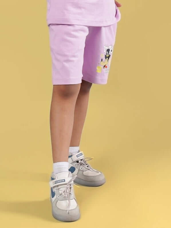 Child wearing WOLF PACK SHORTS FOR BOYS & GIRLS LILAC standing on a yellow background