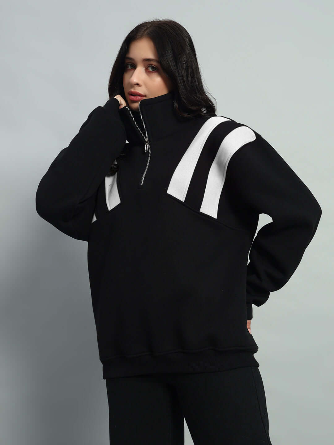 Woman wearing a black and white fleece colorblock jacket with crossbar design, featuring a high neck zip-up collar, stylish and cozy.