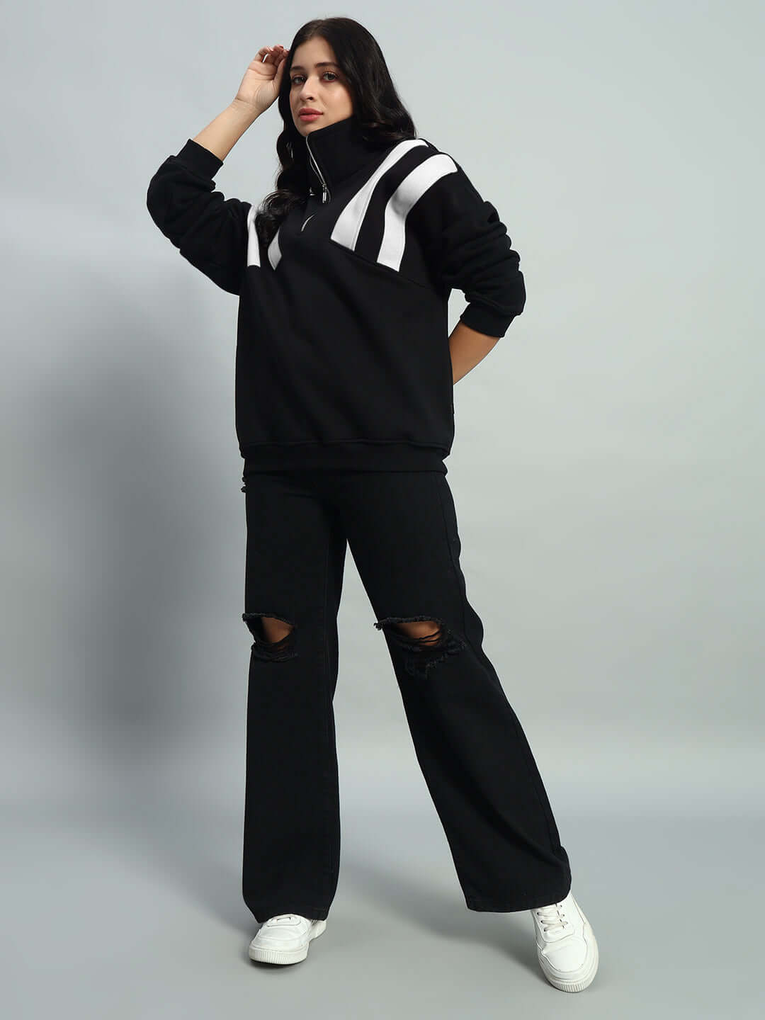 Model wearing women's crossbar fleece colorblock jacket in black and white, paired with black jeans and white sneakers.