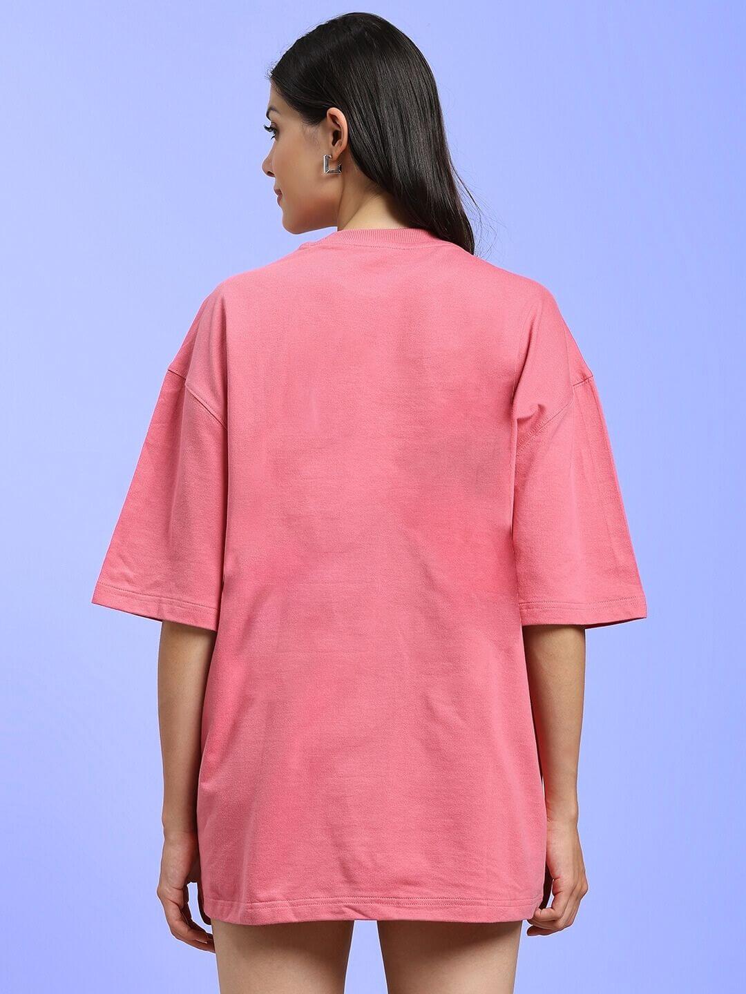 Back view of WOMEN KITSUNE WOLF PRINTED OVERSIZED T-SHIRT PINK on woman, highlighting relaxed fit and pastel color against blue background.