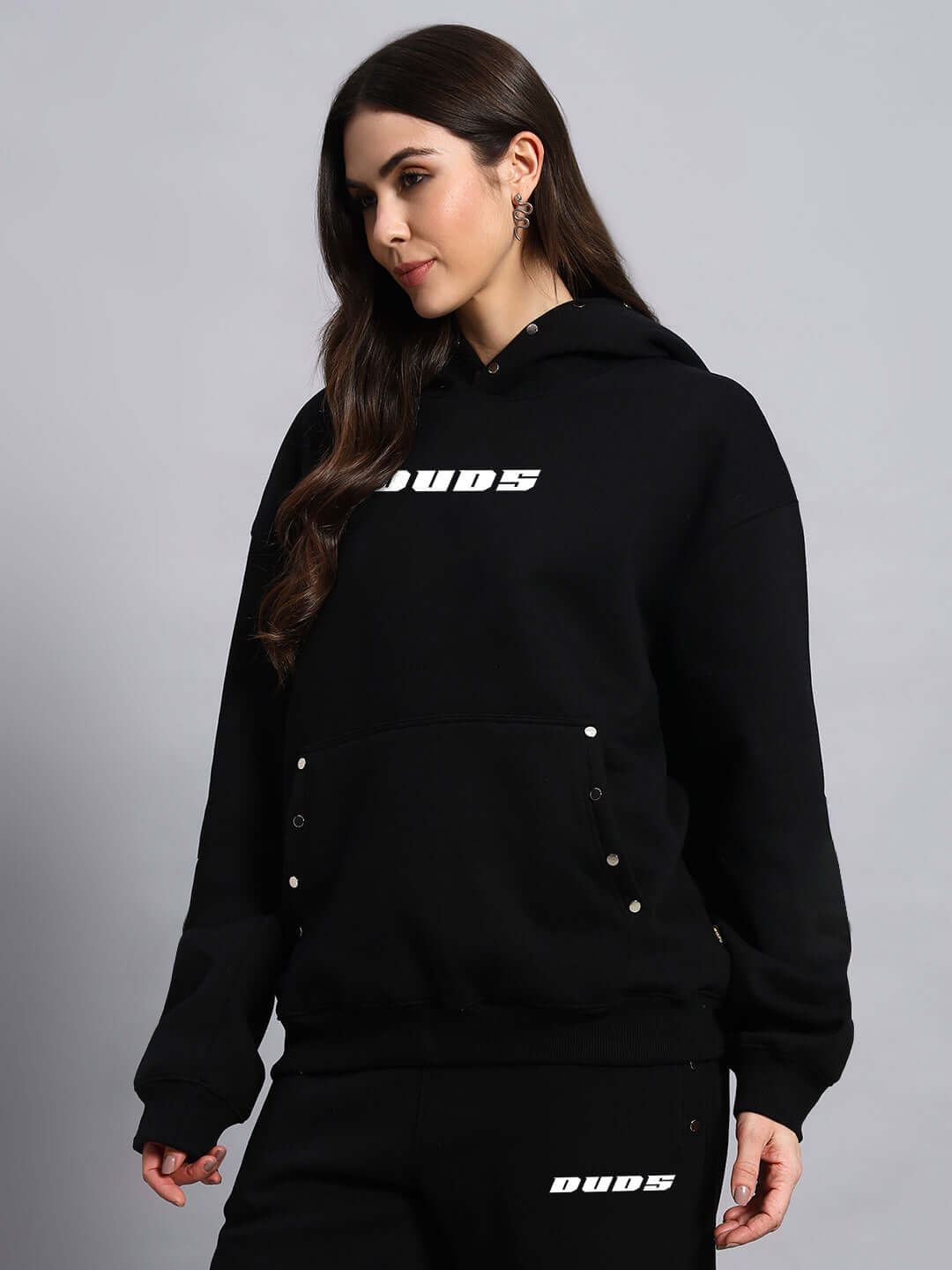 Woman wearing WOMEN RIGID FLEECE HOODIE BLACK by DUDS, showcasing a stylish and cozy design. Custom fit options available.