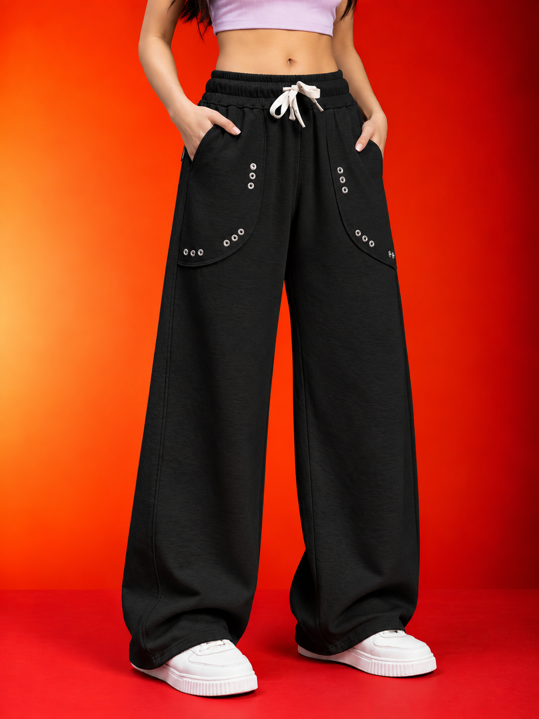 WOMEN EYELET FIT GRAPHIC JOGGERS BLACK with drawstring waist and eyelet pocket detail, styled with white sneakers