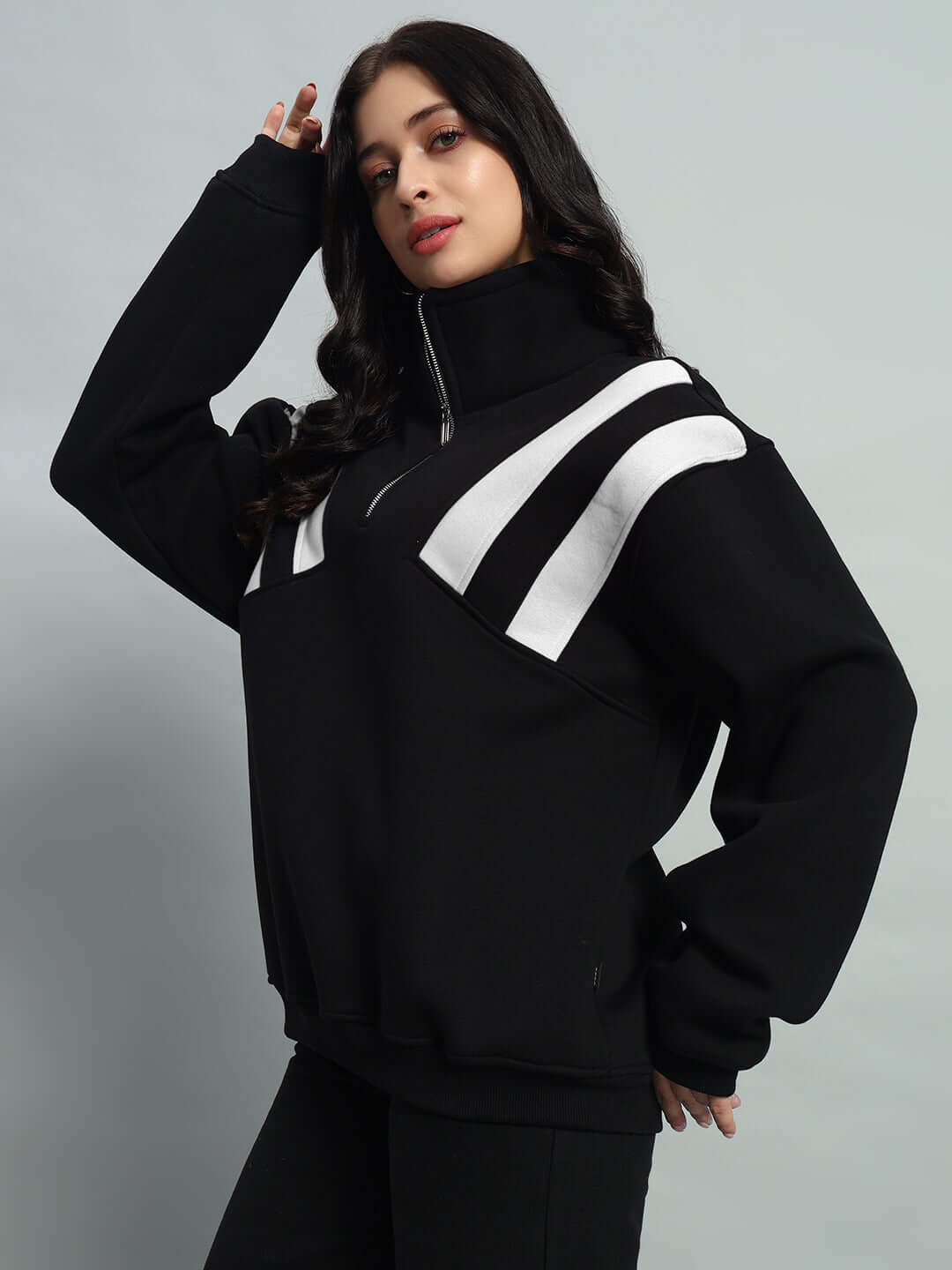 Woman wearing a black and white crossbar fleece colorblock jacket with high collar, posing against a neutral background.