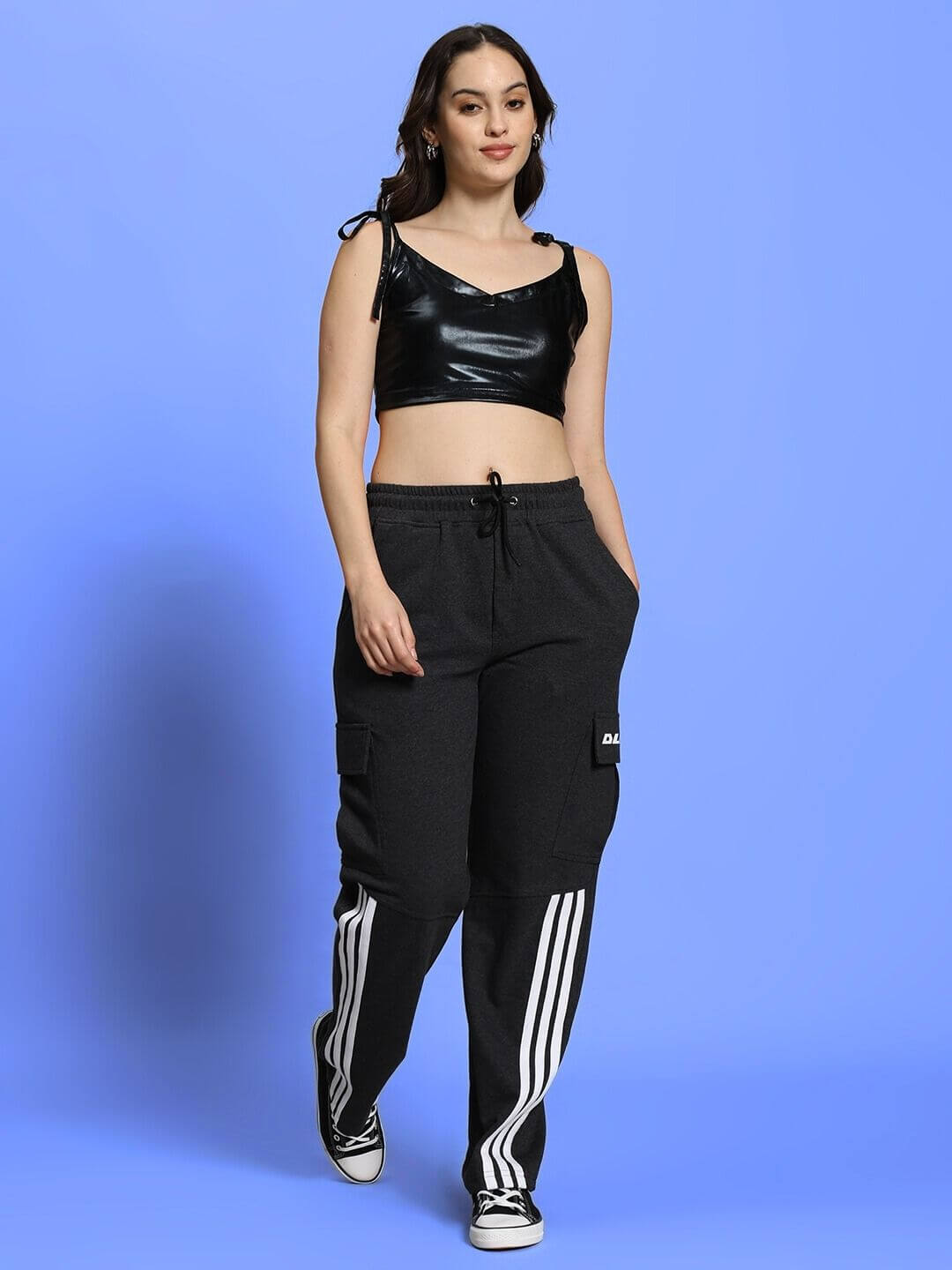 Model wearing Women's Aleena Co-ord Set in black with metallic top and cotton bottoms, styled with sneakers against a blue background.