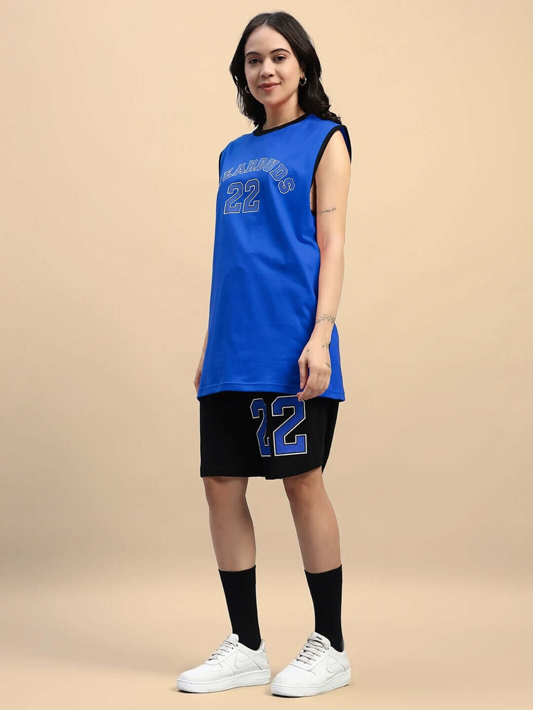 Woman wearing a blue-black gym co-ord set with number 22, made of 100% cotton. Featuring a sleeveless top and shorts. Casual athletic wear.