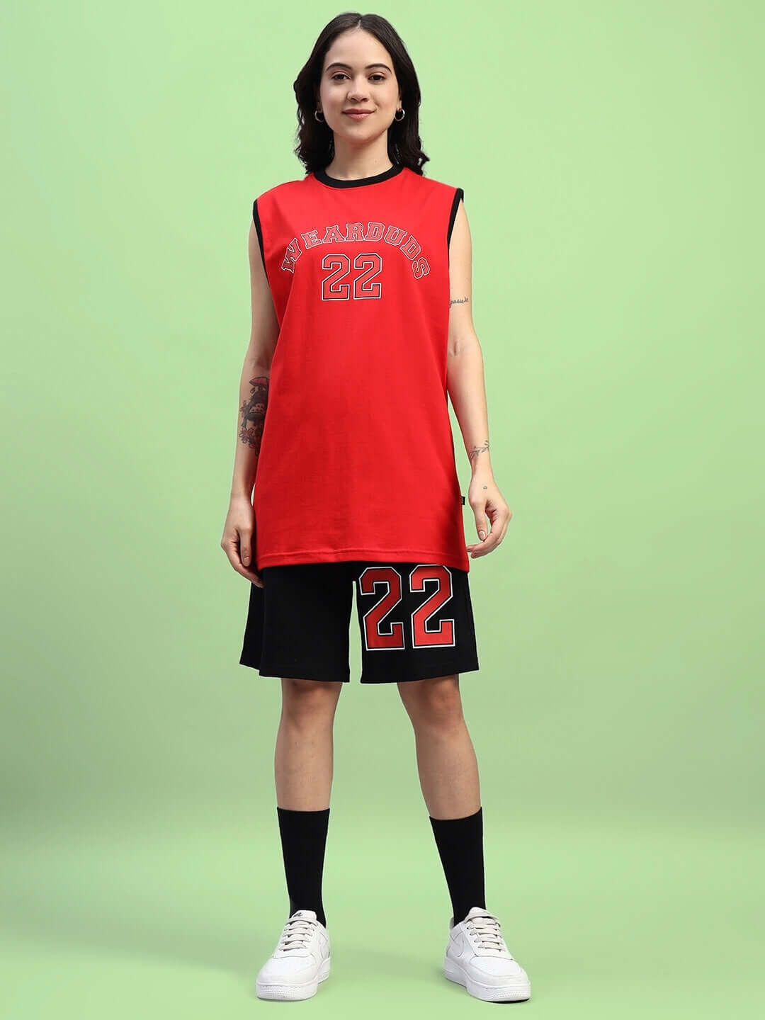 Woman wearing WOMEN'S AMIGA GYM CO-ORD SET RED-BLACK, cotton with red top and black shorts, standing on a green background.