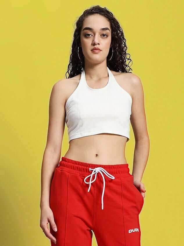 Woman wearing off-white Anissa crop top and red track pants against yellow background.