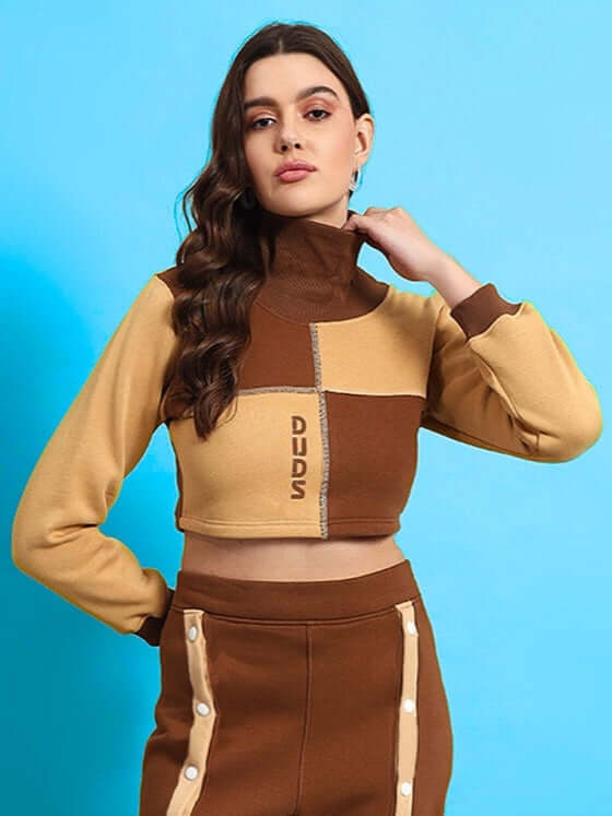 Model wearing Women's Aurora Co-ord Set in beige-brown with high-neck top, showing chic and versatile style against a blue background.