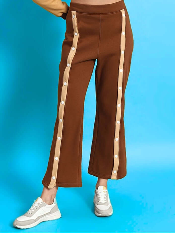 Women's Aurora Fleece Front Open Pant in Beige-Brown with side buttons, displayed on blue background, paired with white sneakers.