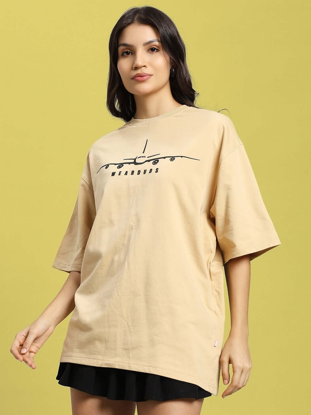Woman wearing a beige oversized aviator designer t-shirt made from premium cotton fabric.