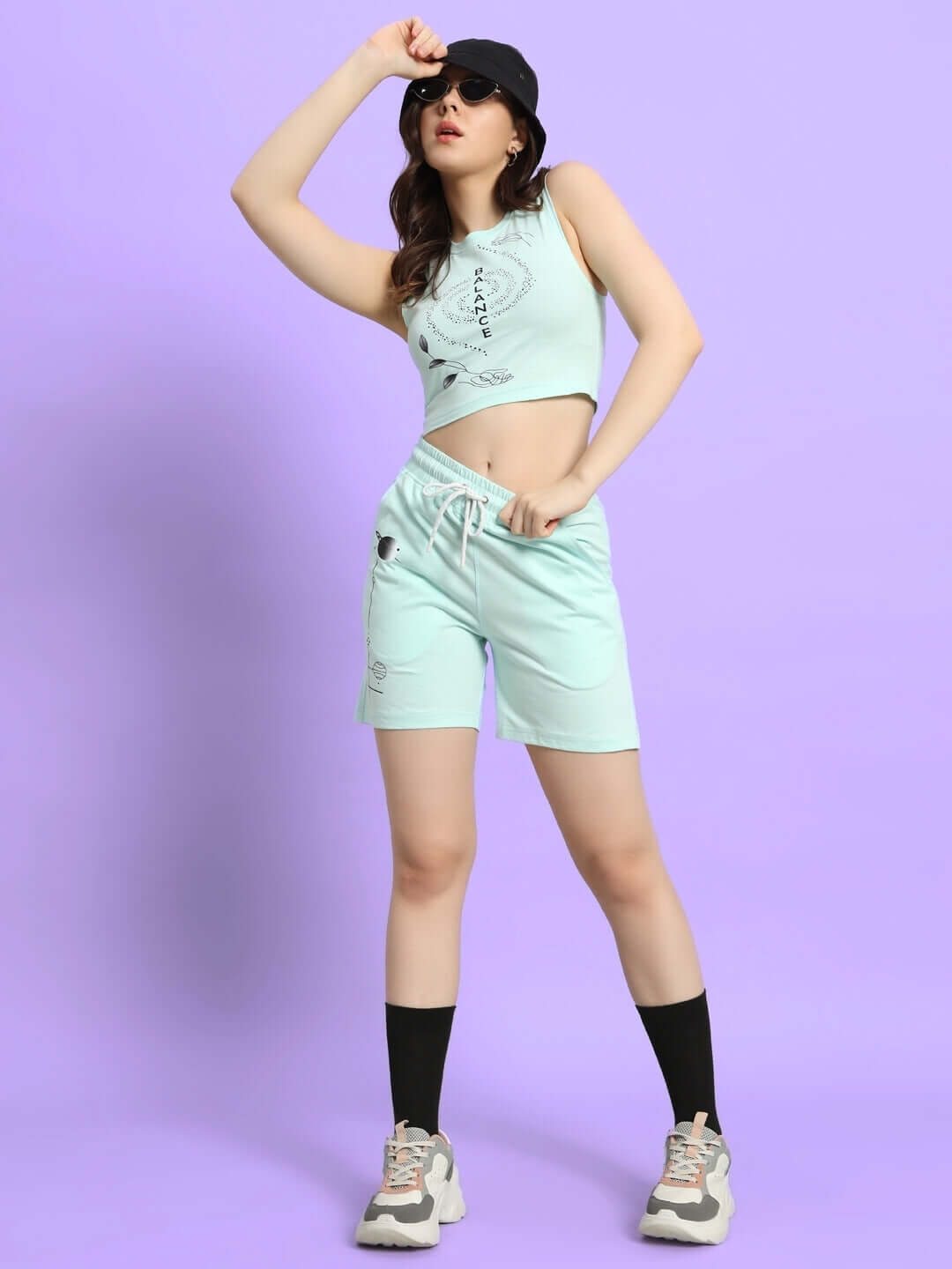 Women's sky blue balance co-ord set with print, made from premium cotton and elastane, model posing with a cap on a soft background.