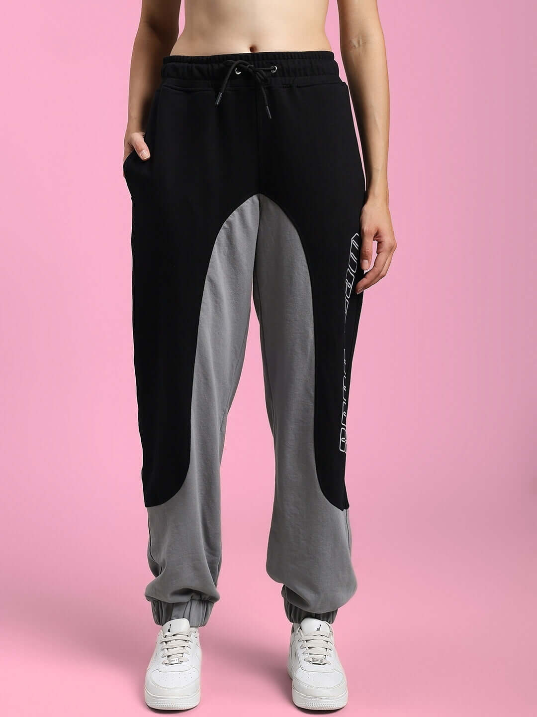 Woman wearing black grey relaxed fit joggers from DUDS on pink background