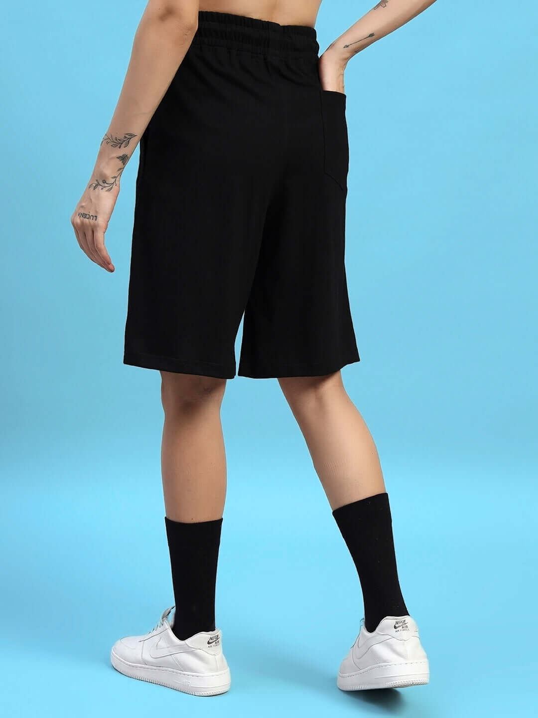 Back view of Women's Amiga Regular Fit Shorts in black, showcasing comfortable fit and style, worn with white sneakers.