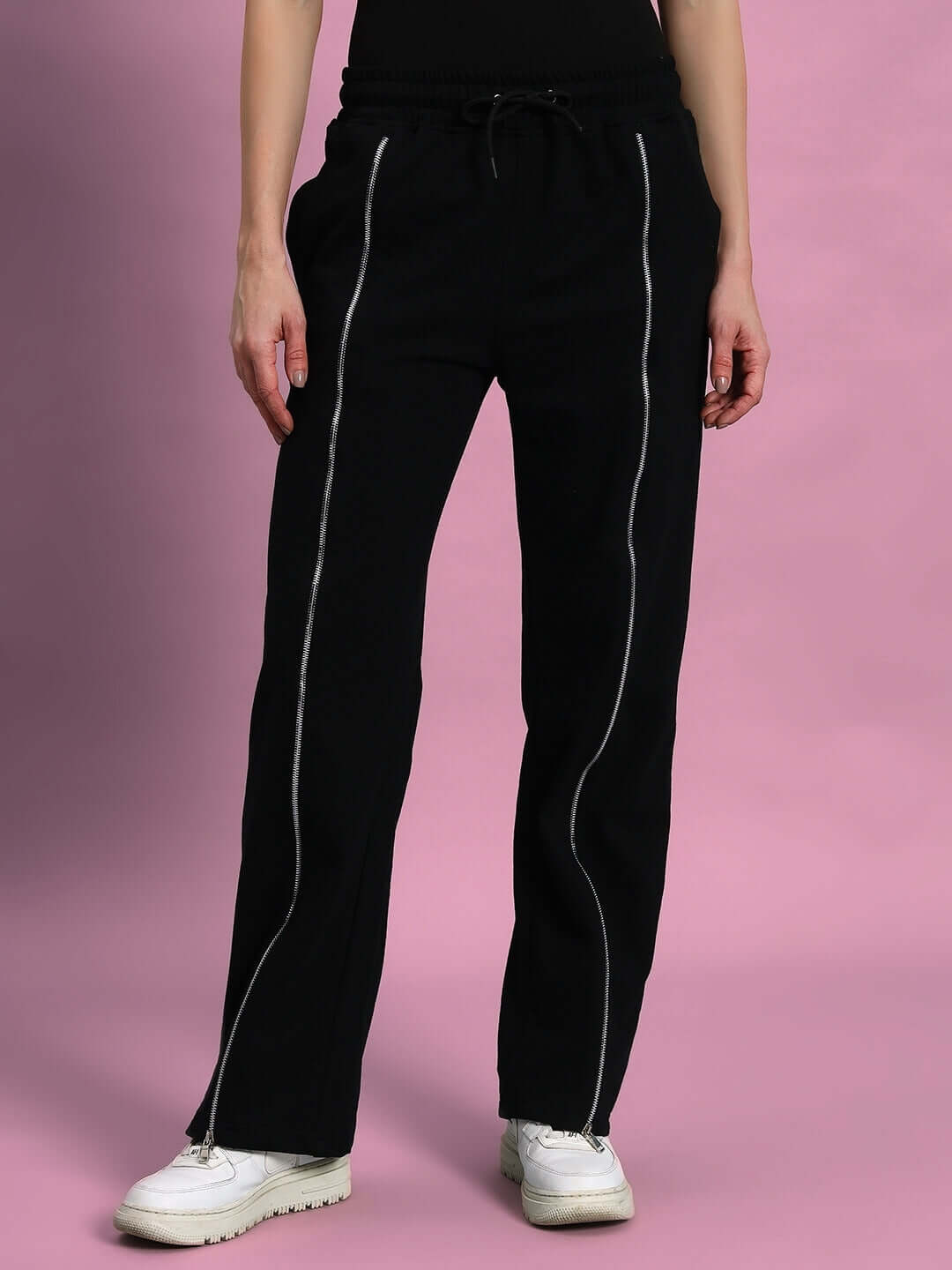 Women's black joggers with front zipper design, tailored by DUDS for a custom fit option, shown against a pink background.