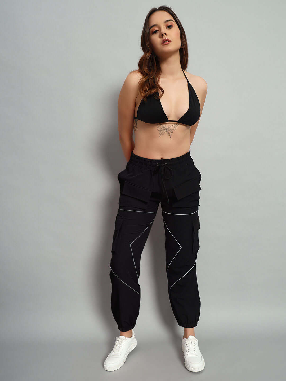Model wearing WOMEN FRONTLINE REFLECTOR PARACHUTE CARGO PANTS BLACK, showcasing streetwear style and comfort in a relaxed fit.