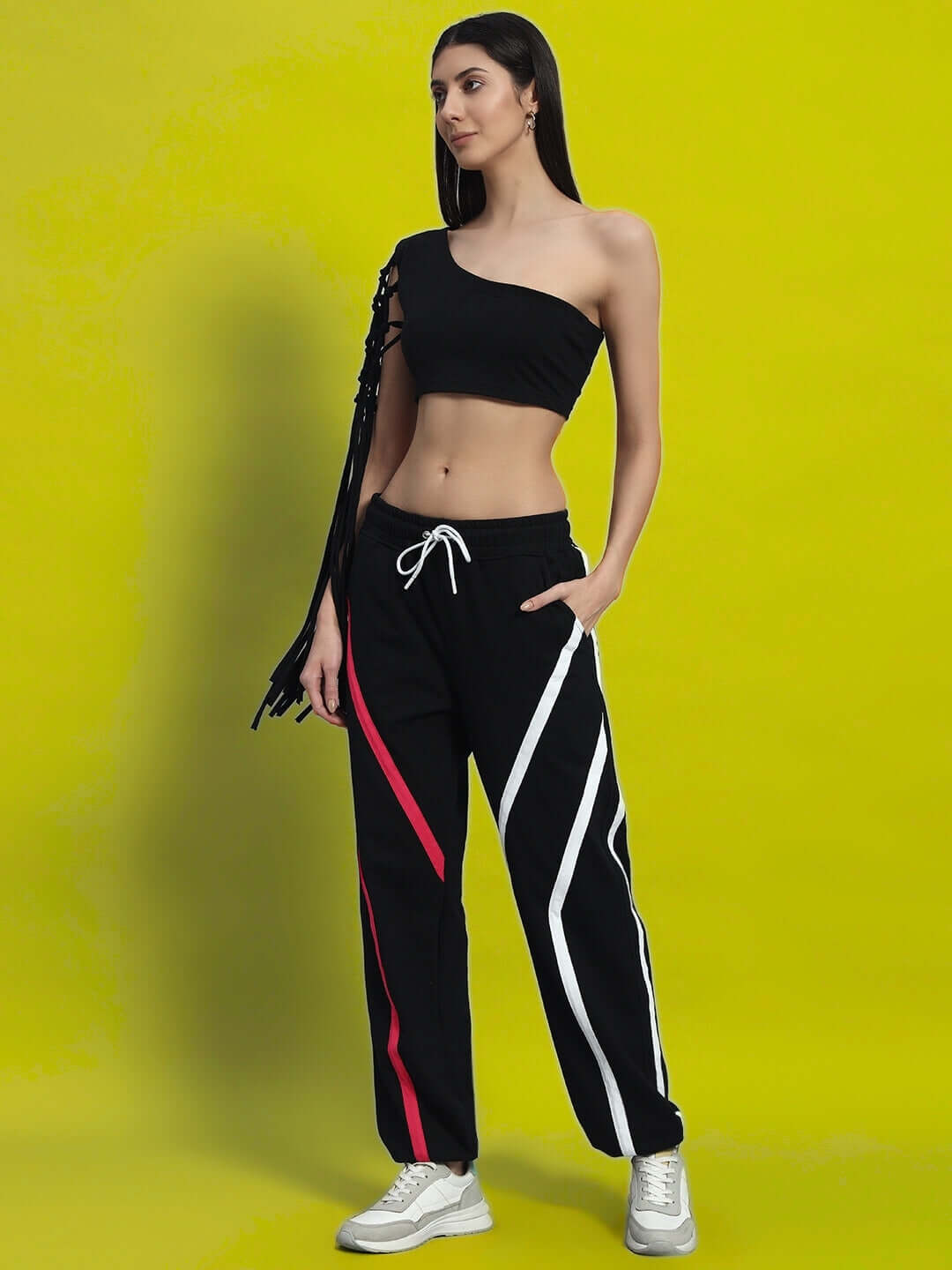Woman wearing a black macrame crop top made from premium heavy gauge fabric, styled with patterned pants, against a yellow background.
