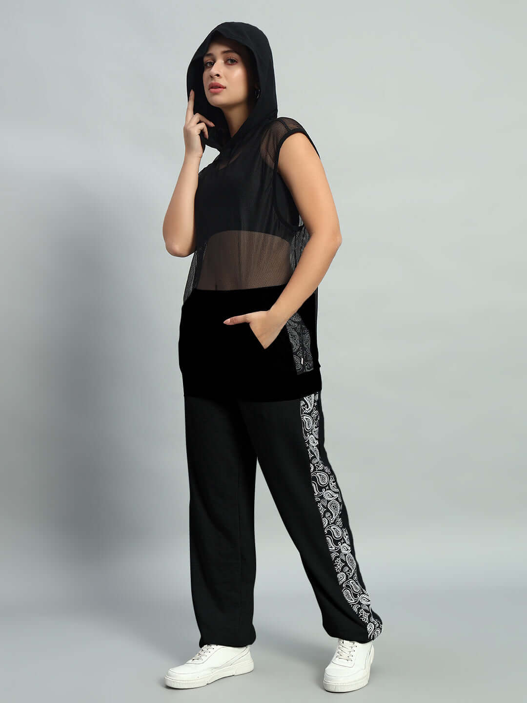 Woman wearing a black oversized co-ord set with hooded top and patterned joggers, featuring elastic waistband and comfortable fit.