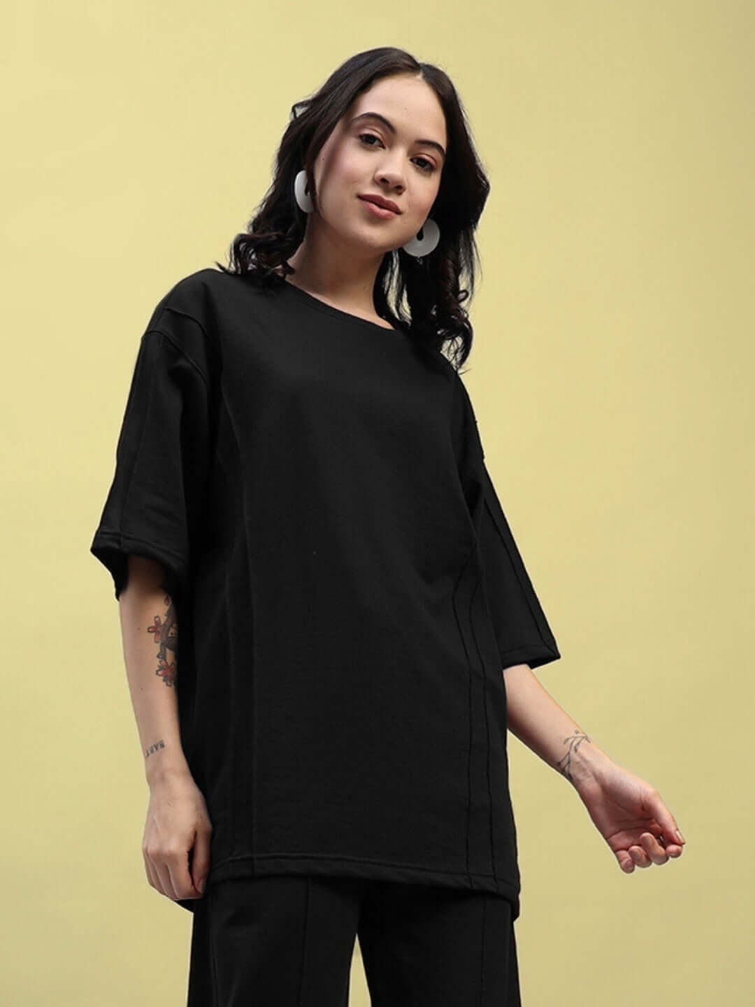 Woman wearing black oversized t-shirt made of 97% cotton with elastane, suitable for casual wear, comfortable fit.