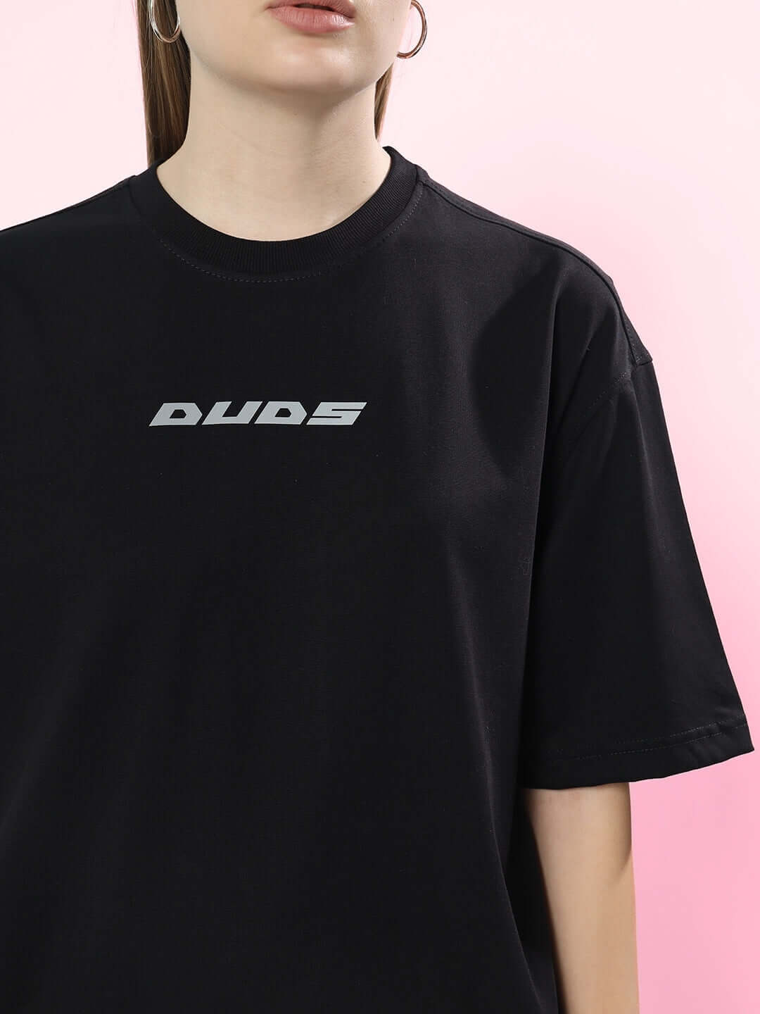 Woman wearing black oversized t-shirt with 'DUDES' logo, made from premium cotton blend. Ideal for casual style. Made in India.