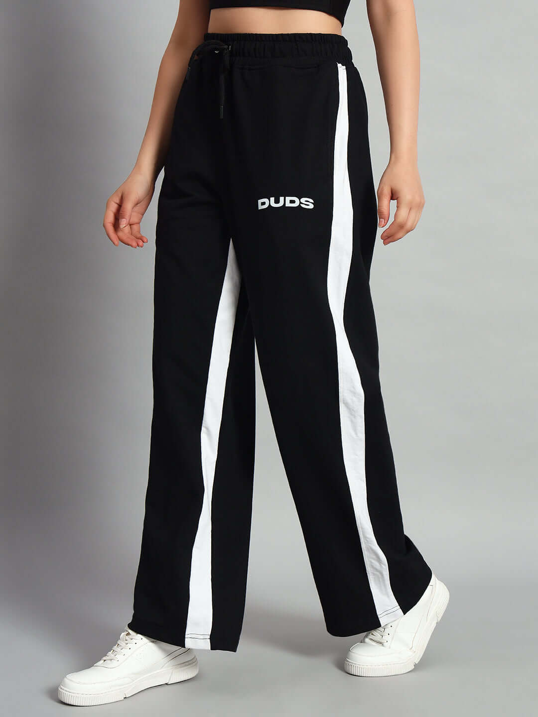 Woman wearing black side seam baggy joggers by DUDS with white stripe, showcasing stylish comfort, customizable for perfect fit.