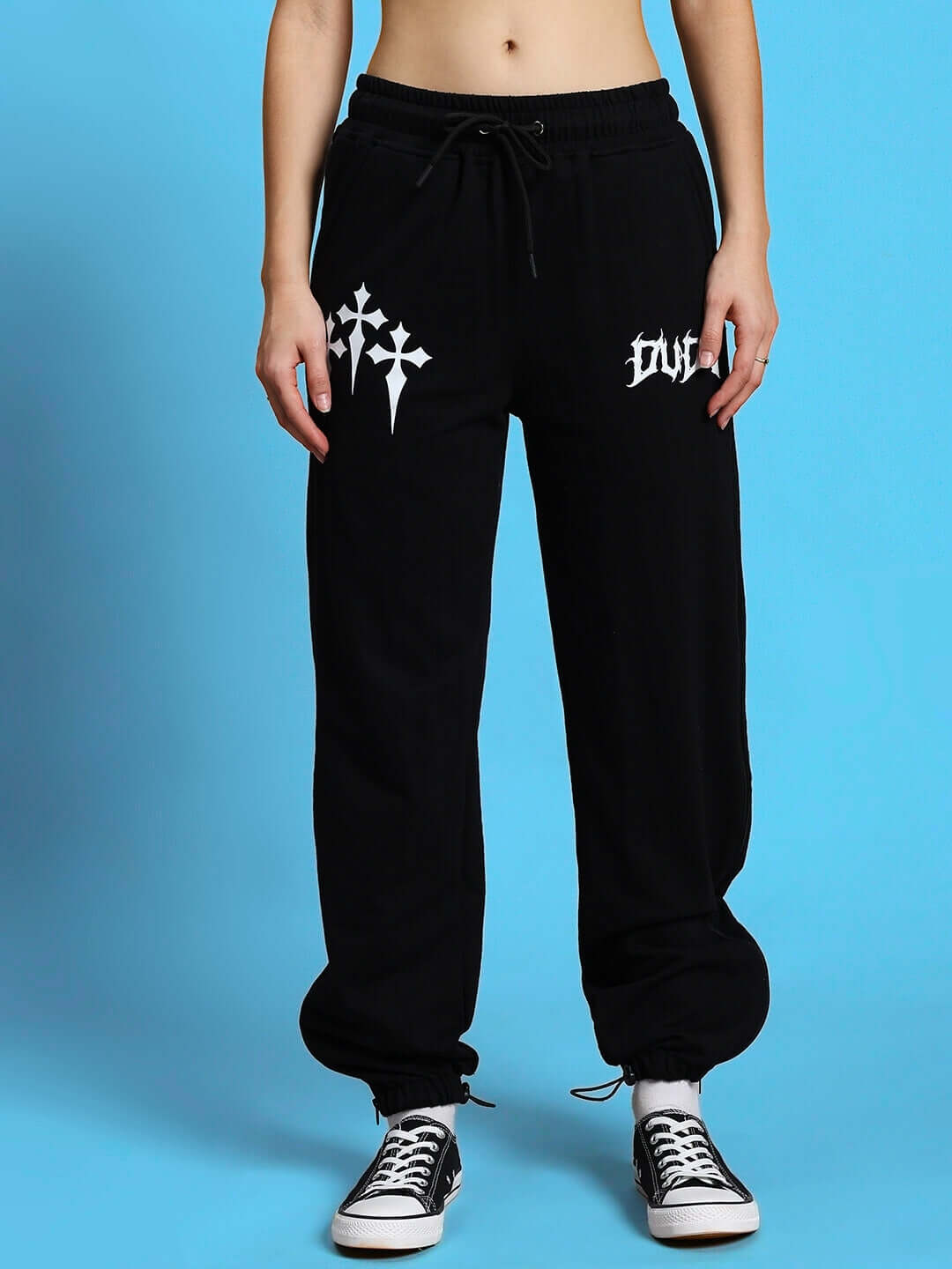 Black joggers with white graphic design and drawstring waist, worn casually with sneakers.