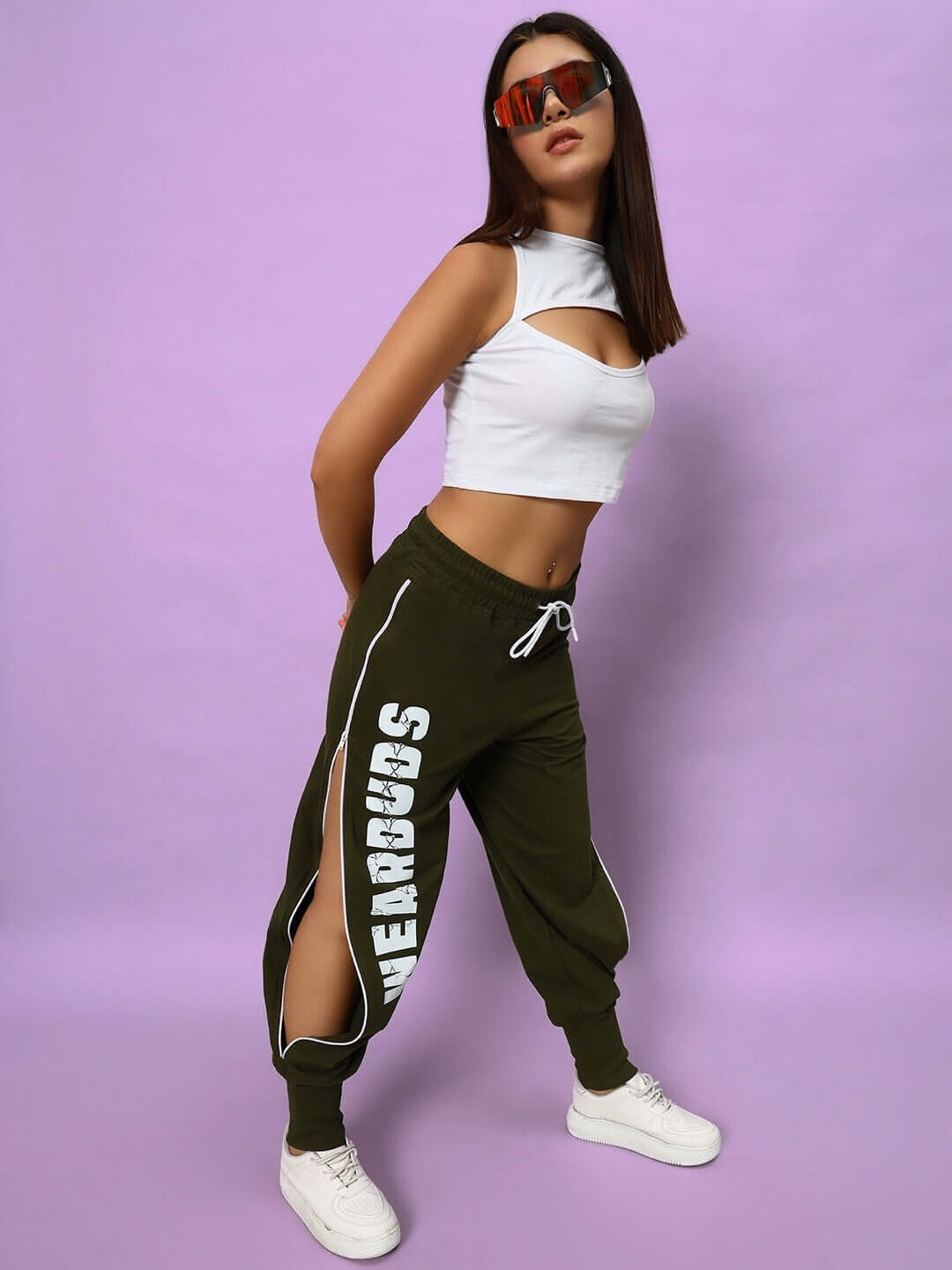 Woman wearing WOMEN BLINK COTTON CROP-TOP WHITE with joggers, against a pink background, showcasing casual chic fashion style.