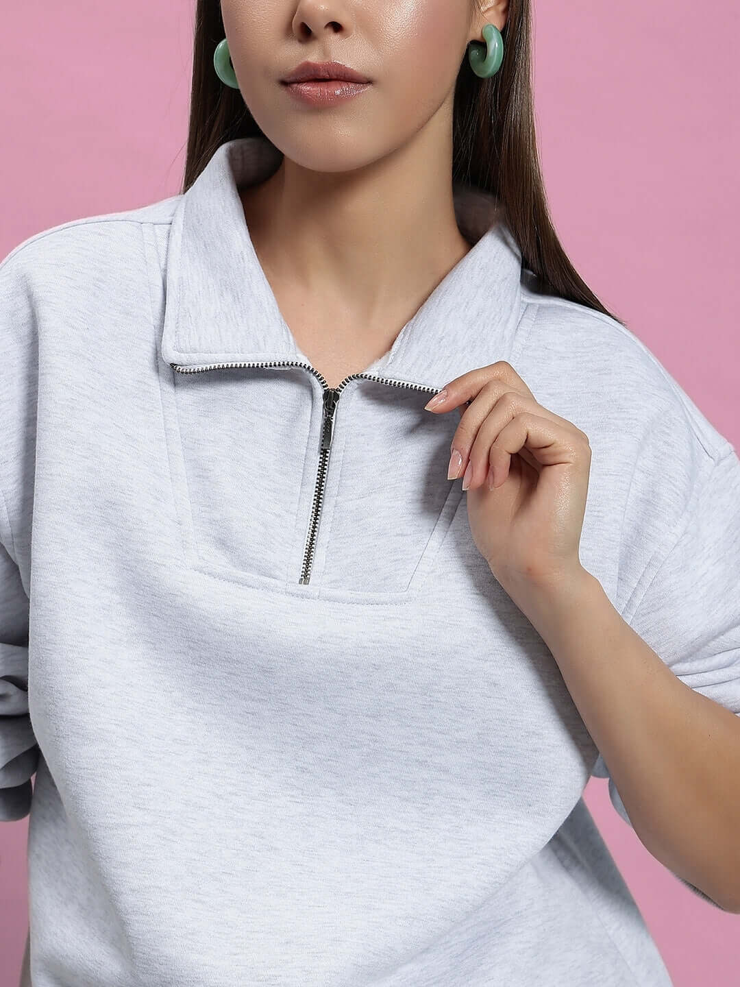 Woman wearing a melange grey fleece top from the Bona-Fide Co-ord collection by DUDS with a pink background.