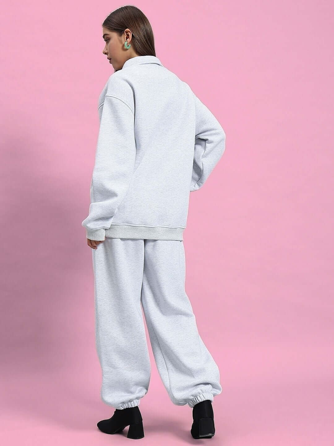 Model wearing Women's Bona-Fide Fleece Co-Ord in melange grey, showcasing comfortable made-to-order fashion by DUDS on pink background.
