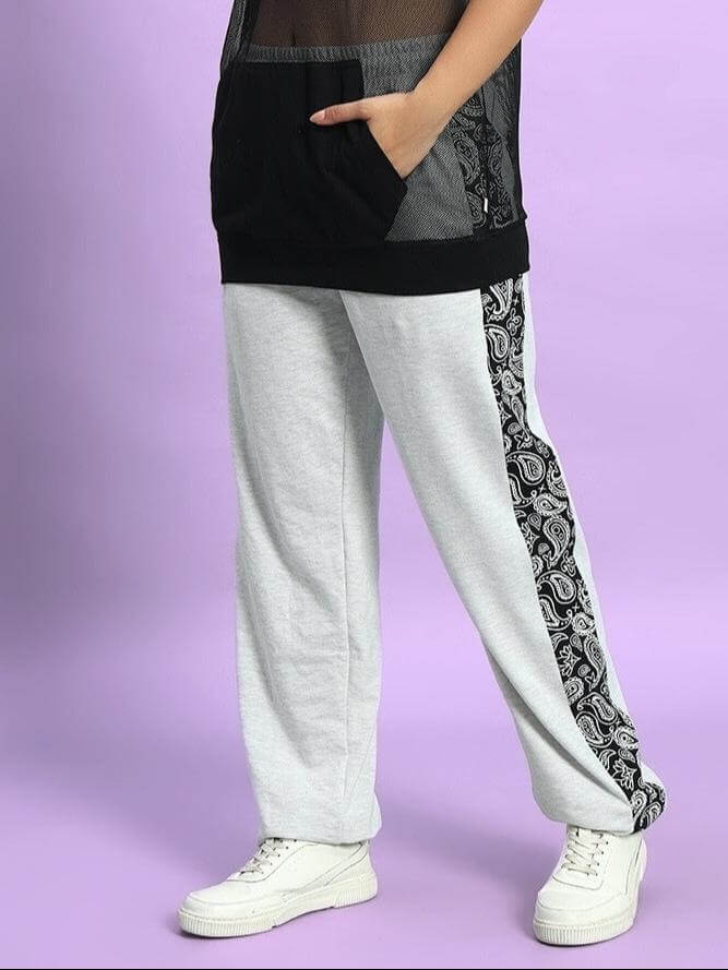 Women's Boogie Relaxed Fit Joggers in Melange Grey with paisley sides, styled with white sneakers on a purple background.