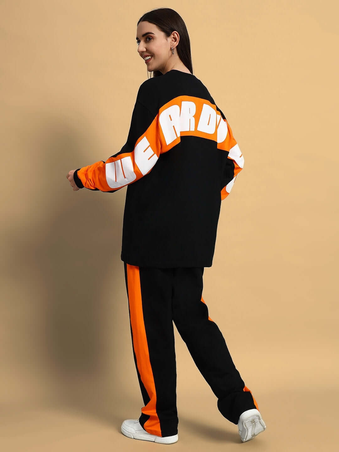Woman wearing black and orange oversized co-ord set with matching joggers, showcasing a stylish streetwear look from the back view.