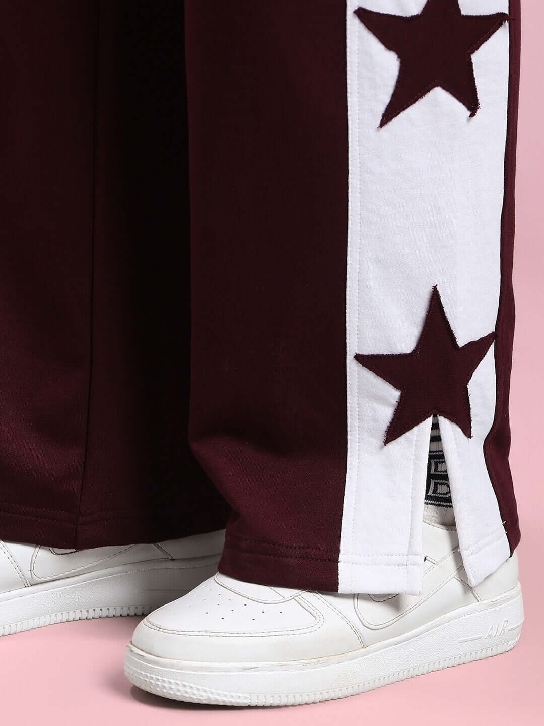 Women's maroon joggers with white star design and relaxed fit, paired with white sneakers, showcasing stylish casual wear.