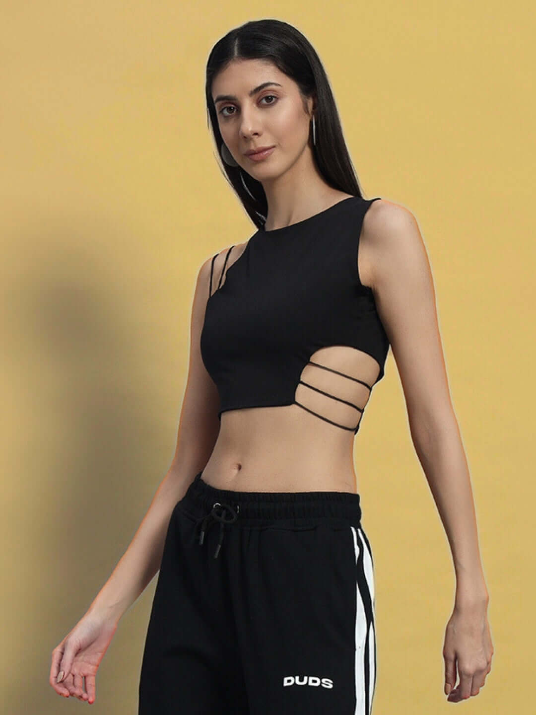 Black women's crop top made from premium heavy gauge fabric, featuring side cutouts, modeled in front of a warm yellow background.