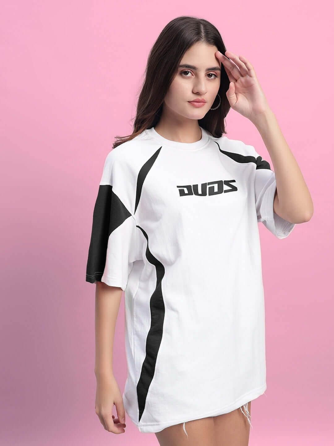 Women's oversized white T-shirt with black detailing, made of premium cotton fabric. Model poses in front of pink background.