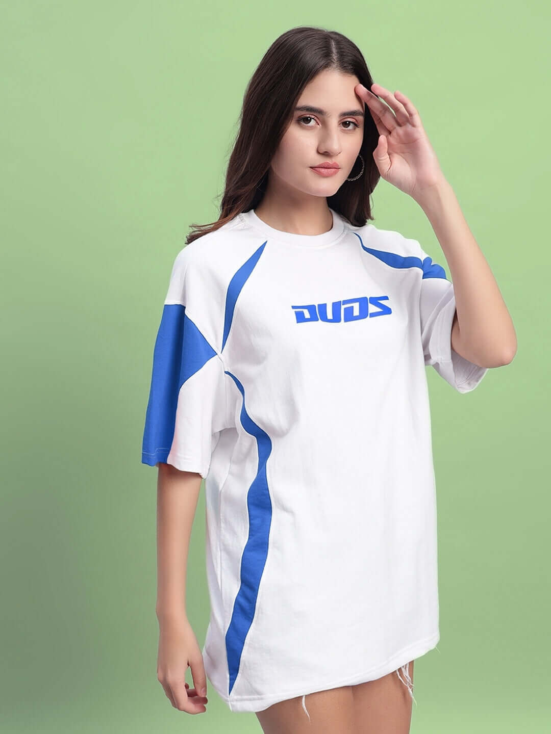 Model wearing Women's Candor Over-Sized T-Shirt in white and blue, made from premium cotton fabric. Made in India. Vibrant design on green background.