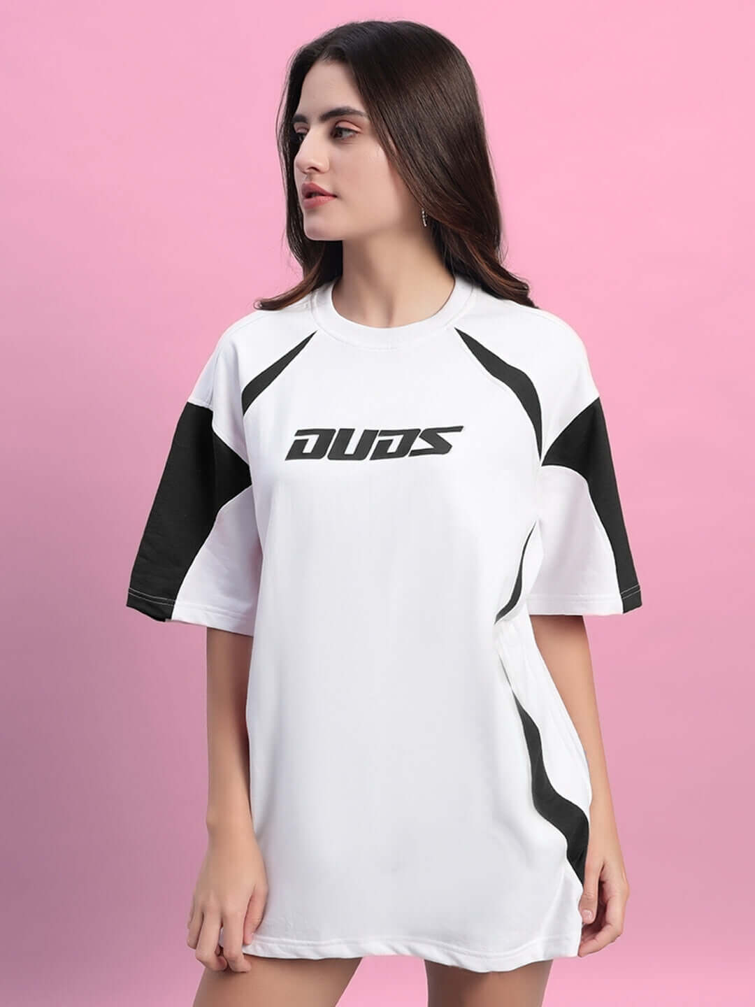 Woman wearing oversized women's candor T-shirt in white and black, made from premium cotton and elastane, against a pink background.