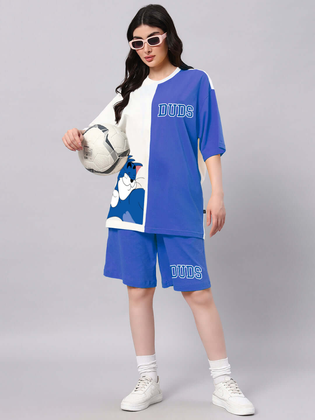 Woman wearing a blue and off-white co-ord set playing soccer, featuring premium cotton and elastane fabric, by Color By.